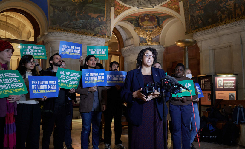 Assemblymember Michaelle Solages at a rally in Albany's State Capitol for the Build Public Renewables Act, with other supporters behind her.