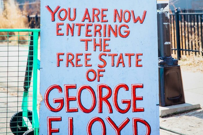 A free-standing sign near an intersection with red letters that read "YOU ARE NOW ENTERING THE FREE STATE OF GEORGE FLOYD"