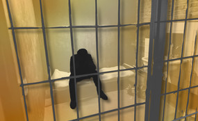 A person inside an extremely hot prison cell sits hunched over.