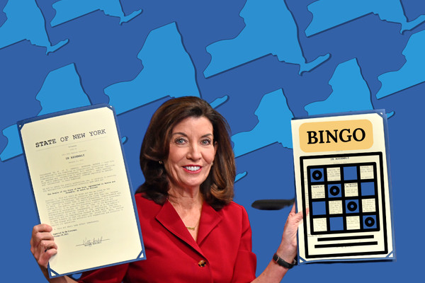 Kathy Hochul holding up papers in each hand. One hand has an official State of New York document and the other is a Bingo game card that was illustrated.