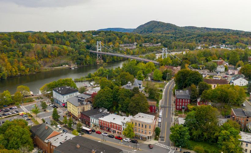 An overhead view shows streets, buildings, trees, and a river in the forested town of Kingston, New York, the Ulster County seat.