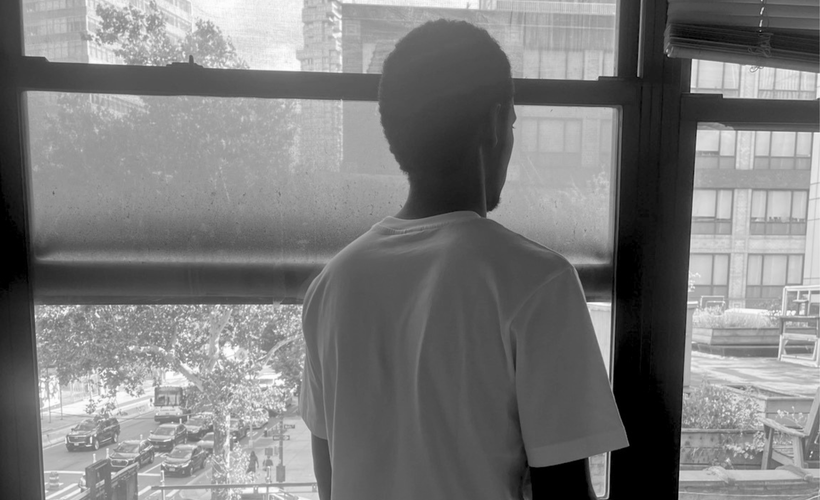 Theirno sits at a table, looking over his shoulder out of the window.