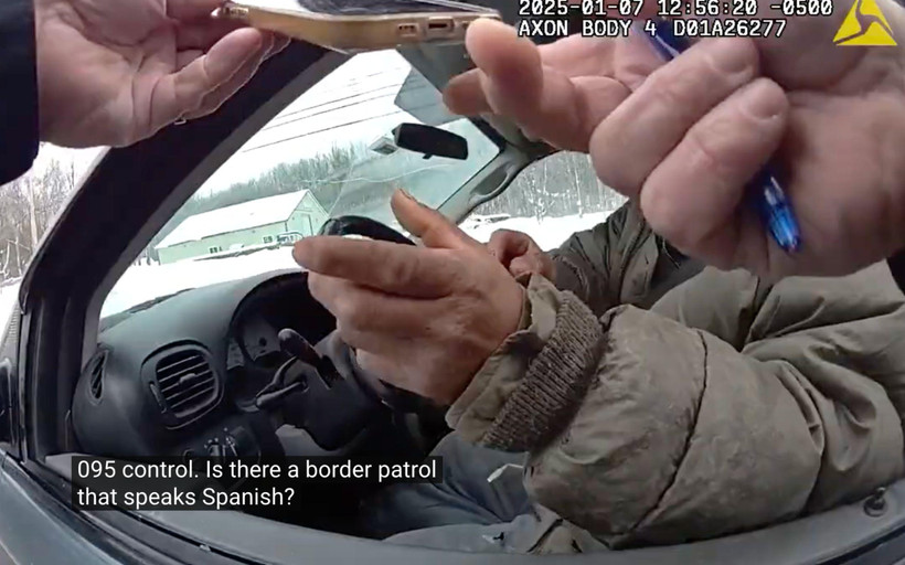 A screenshot from a police body camera shows a person in a car, his face obscured by the officer's hands holding a phone. The caption shows the officer saying "Is there a border patrol that speaks Spanish?"