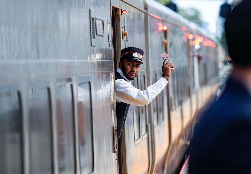 A Long Island Rail Road conductor standing inside a train gestures with his hand.