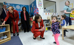 New York governor Kathy Hochul kneels in a red suit with a child looking out in distress