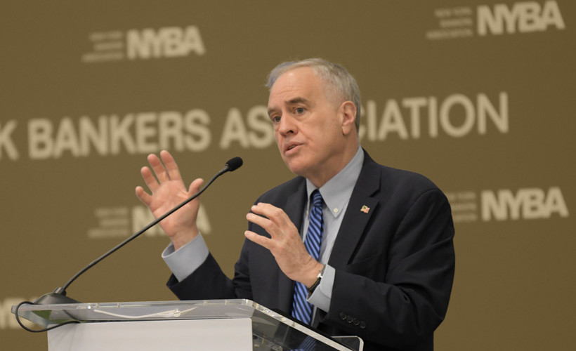 Comptroller Tom DiNapoli speaks at a podium, gesticulating with his hands.
