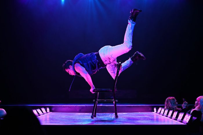 Man arm balances on chair with legs up