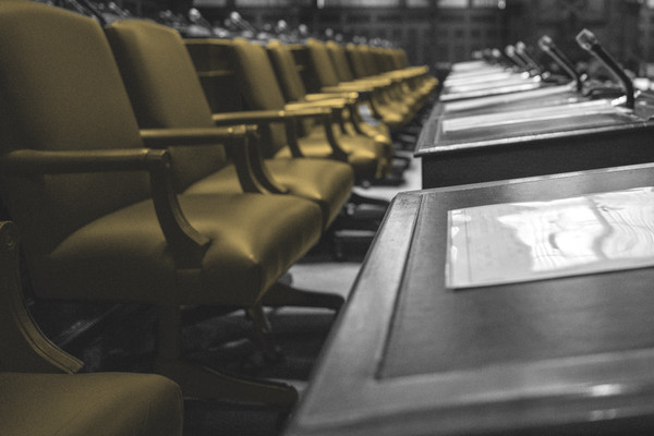 Image of a legislative chamber with many empty chairs.