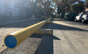 A yellow gas pipe stretches aboveground along a street.