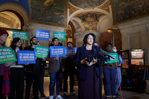 Assemblymember Michaelle Solages at a rally in Albany's State Capitol for the Build Public Renewables Act, with other supporters behind her.
