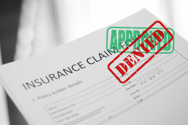 An insurance claim has first been stamped "approved," but then stamped "denied."