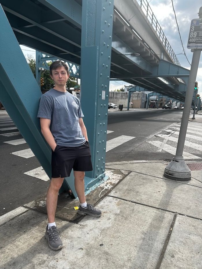 A person leans against a bridge in bright daylight