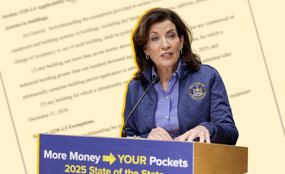 Kathy Hochul stands in front of the blurred out text of a bill draft.