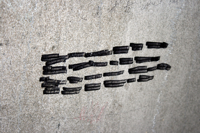 A gray cement wall with black marker lines on it.