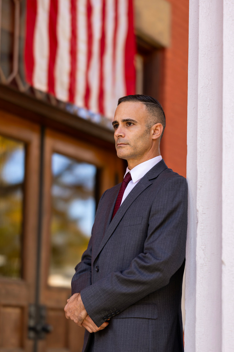 Yates County District Attorney Todd Casella with a stern face. He is a white man with short, dark brown hair, thick brown eyebrows and dark brown eyes.
