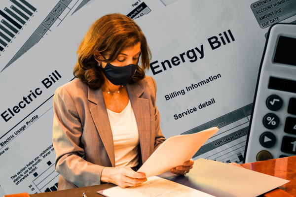 Hochul reading a piece of paper against the backdrop of energy bills