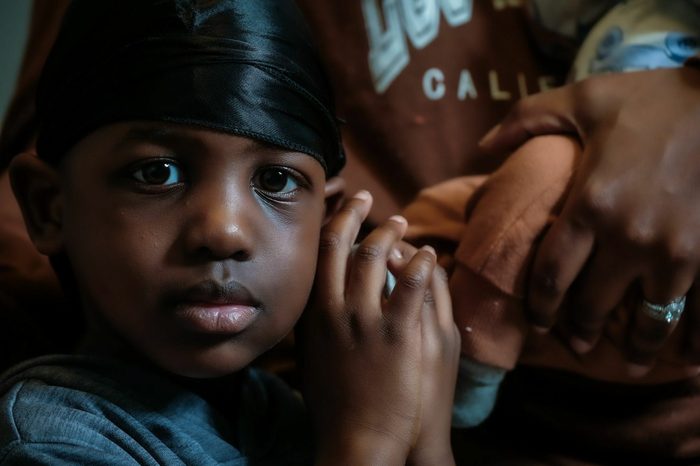 Young boy with a black head scarf looking directly at the viewer