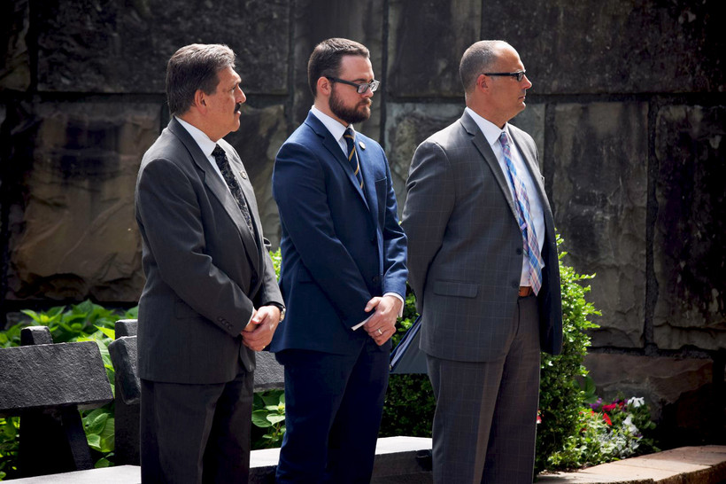 Three men in suits, including former acting prison commissioner Anthony Annucci and acting prison commissioner Daniel Martuscello III, stand at a memorial ceremony in Albany.