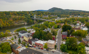 An overhead view shows streets, buildings, trees, and a river in the forested town of Kingston, New York, the Ulster County seat.
