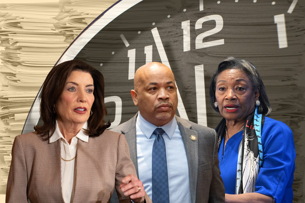 Photo collage of Governor Kathy Hochul, Assembly Speaker Carl Heastie, and Senate Majority Leader Andrea Stewart-Cousins. Behind them, a huge clock nears midnight, and stacks of papers loom.