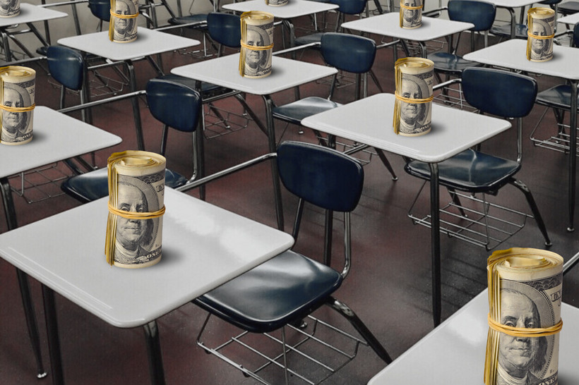 Rows of desks in a classroom with a roll of dollar bills on each desk.