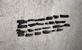 A gray cement wall with black marker lines on it.