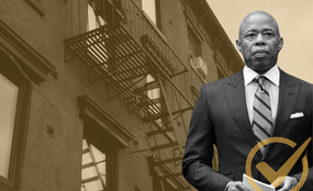 Mayor Eric Adams standing in front of an apartment building.