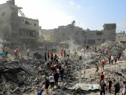 In a wide-angle photograph, people walk through a sea of rubble.