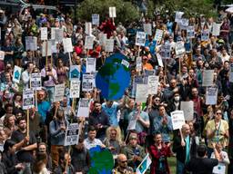 A large group of Amazon workers rally in front of Amazon's headquarters in Seattle on May 31, 2023, citing the company's changes to its climate policy, layoffs, and a return-to-office mandate. Some people hold what appear to be cardboard globes. Others hold picket signs.