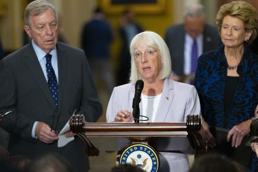 Patty Murray speaks at a podium, flanked by two officials.