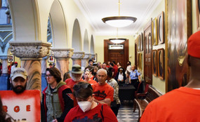 Rochester, NY residents dressed in red with the group Metro Justice wait at the city council in June.