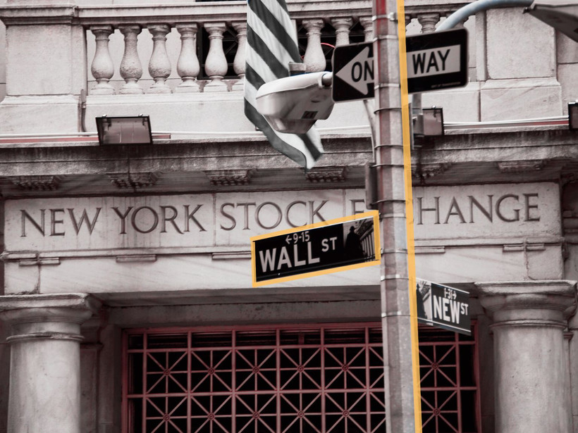 A photo illustration showing the New York Stock Exchange building and the street sign for Wall Street.