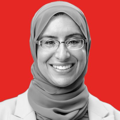 Maha Nassar is smiling at the camera. She is wearing a hijab and glasses.