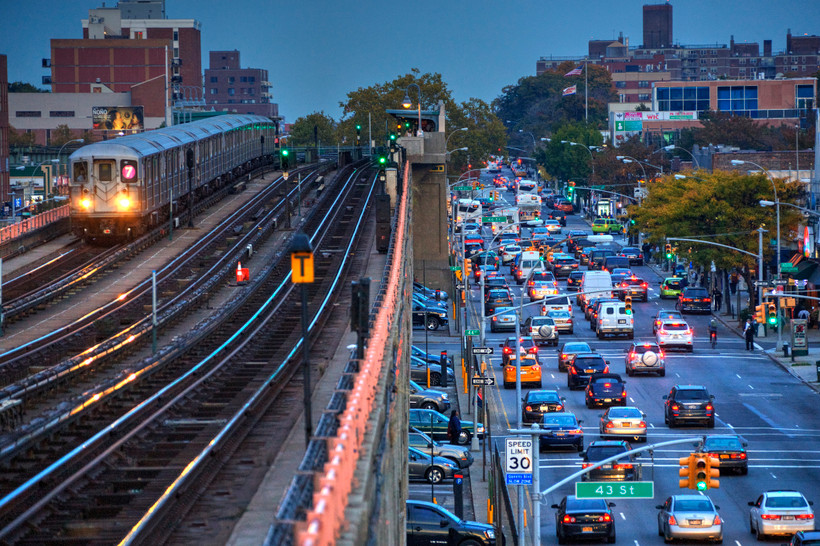 A New York City subway on the left, and highway traffic on the right.