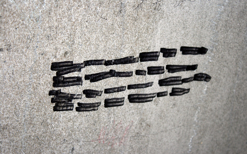 A gray cement wall with black marker lines on it.