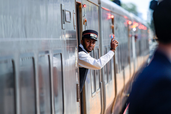 A Long Island Rail Road conductor standing inside a train gestures with his hand.
