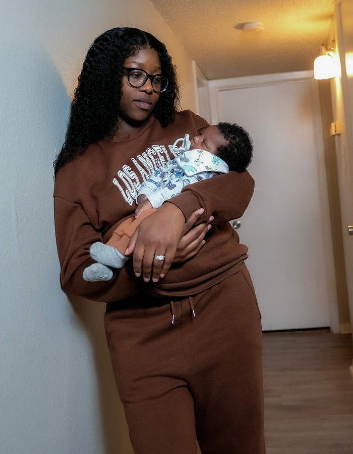 Woman with glasses standing while holding her infant child in her arms