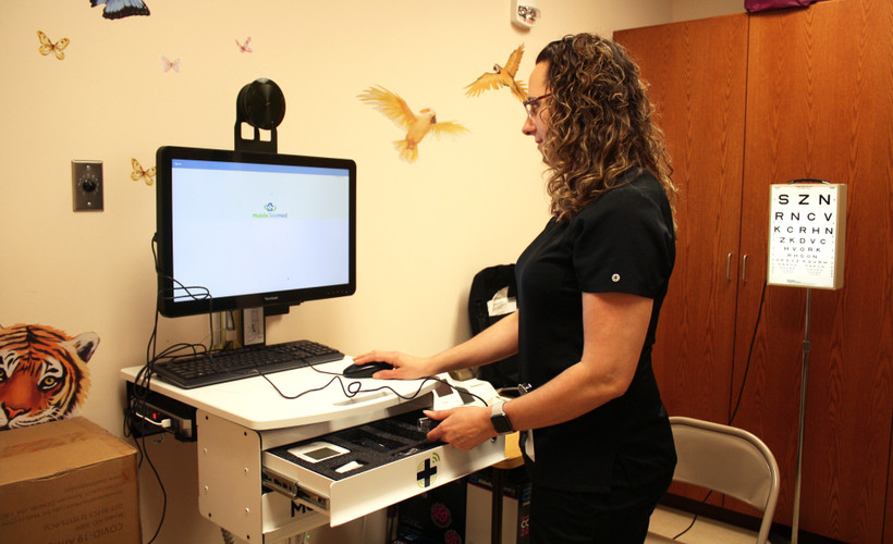 A nurse stands at a computer in a school nurse's office