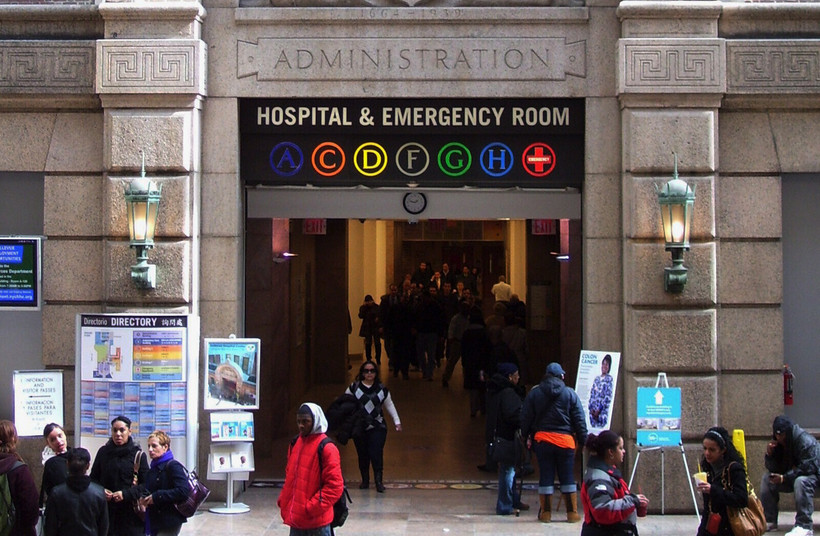 People gather outside a stone arch with sign that says "Hospital & Emergency Room" displaying letters A, C, D, F, G, H, and an emergency cross.