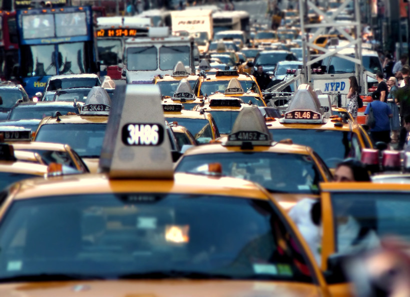 The image depicts a traffic jam in New York City, with a cluster of yellow taxi cabs at the front.