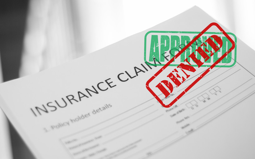 An insurance claim has first been stamped "approved," but then stamped "denied."