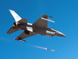 An F-16 in a clear blue sky fires a missile downward.