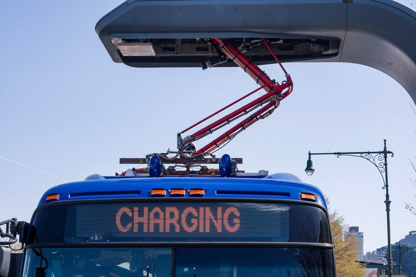 An electric MTA bus is charging at an electric charging port.