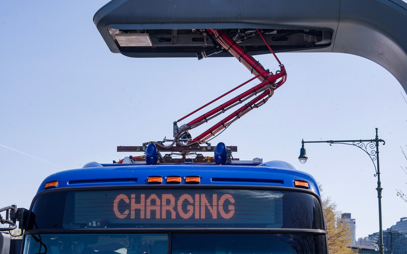 An electric MTA bus is charging at an electric charging port.