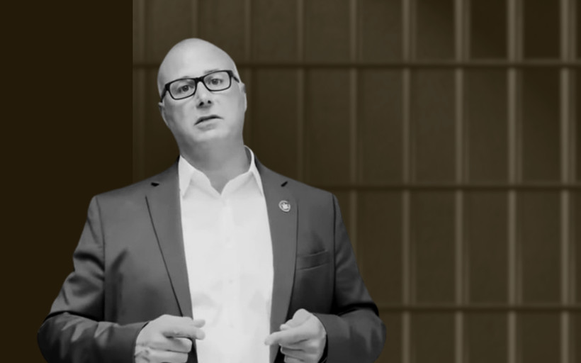 Prison Commissioner Daniel Martuscello III stands in front of prison bars.
