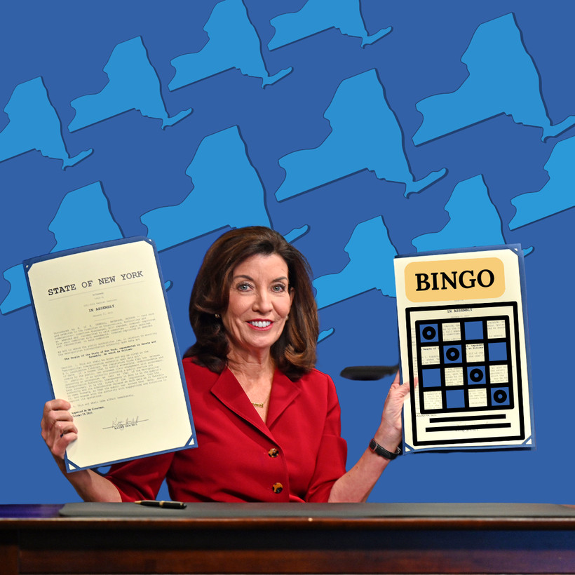 Kathy Hochul holding up papers in each hand. One hand has an official State of New York document and the other is a Bingo game card that was illustrated.
