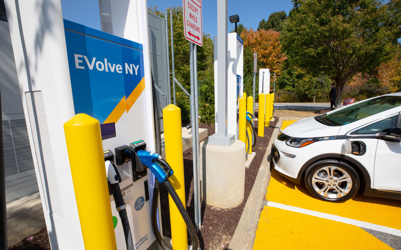A photo of an electric charging station with an "EVolve NY" banner
