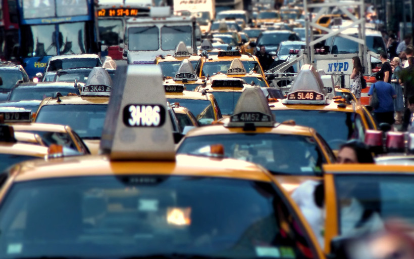 The image depicts a traffic jam in New York City, with a cluster of yellow taxi cabs at the front.