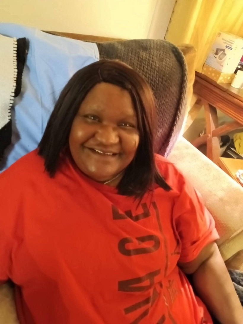 Michelle Woolfolk sits in a chair, wearing a red t-shirt, and smiles towards the camera.