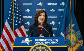 New York City Governor Kathy Hochul stands behind a podium reading "Combatting the Opioid Epidemic"